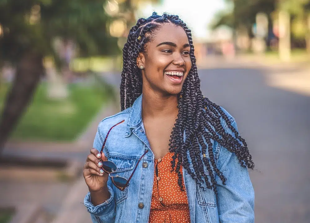 girl smiling outside while walking down the street holding glasses.