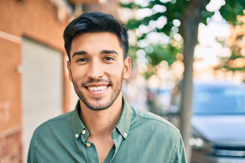 guy standing outside while smiling showing off his teeth
