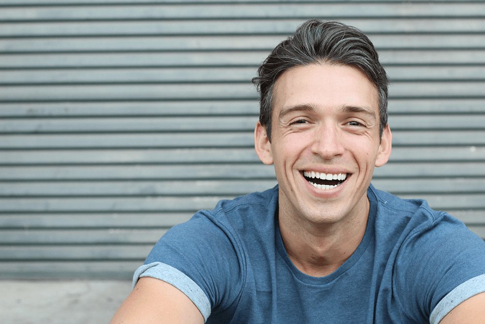 guy sitting outside smiling showing off his new smile