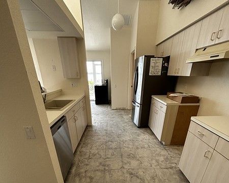 A picture of a kitchen with the old flooring removed, exposing the base layer before the new flooring gets installed.