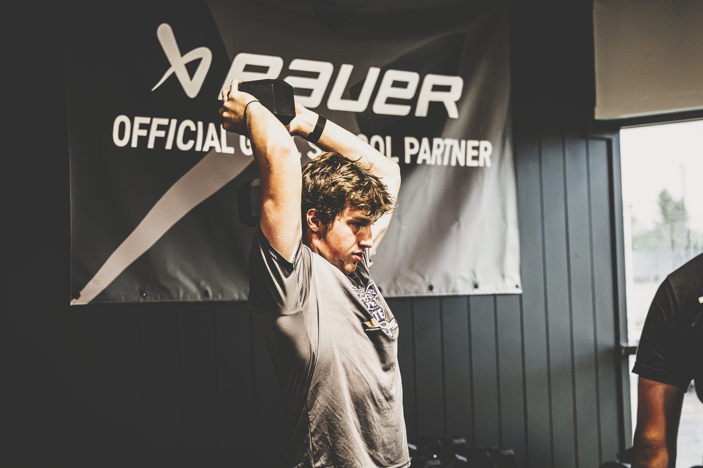 Hockey player doing an overhead dumbbell tricep extension during an in-season training session at Gh