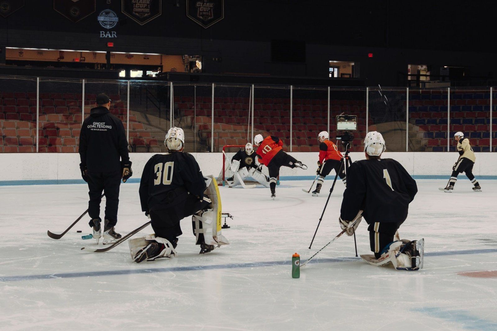 Hockey goalies and skaters receiving instruction during an on-ice training session Hockey goalies and skaters receiving instruction during an on-ice training session