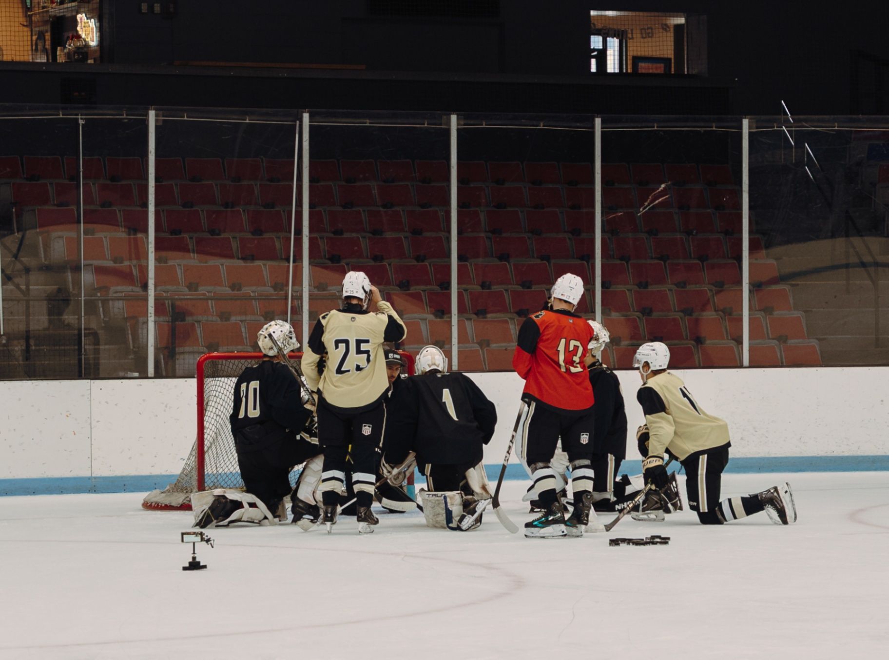 Ghost Athletica goalies gathered around their coach at the net during an on-ice goalie movement training session