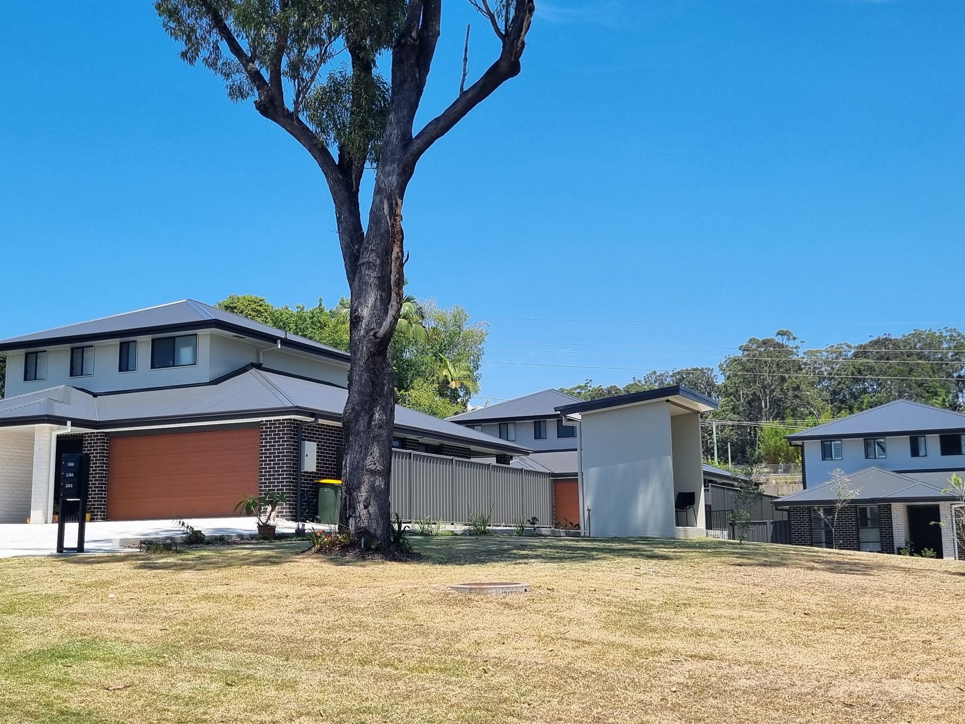 Suburban Homes With Gray Roofs and Brown Garage Doors — Acheson Building Certification in Nambucca Heads, NSW