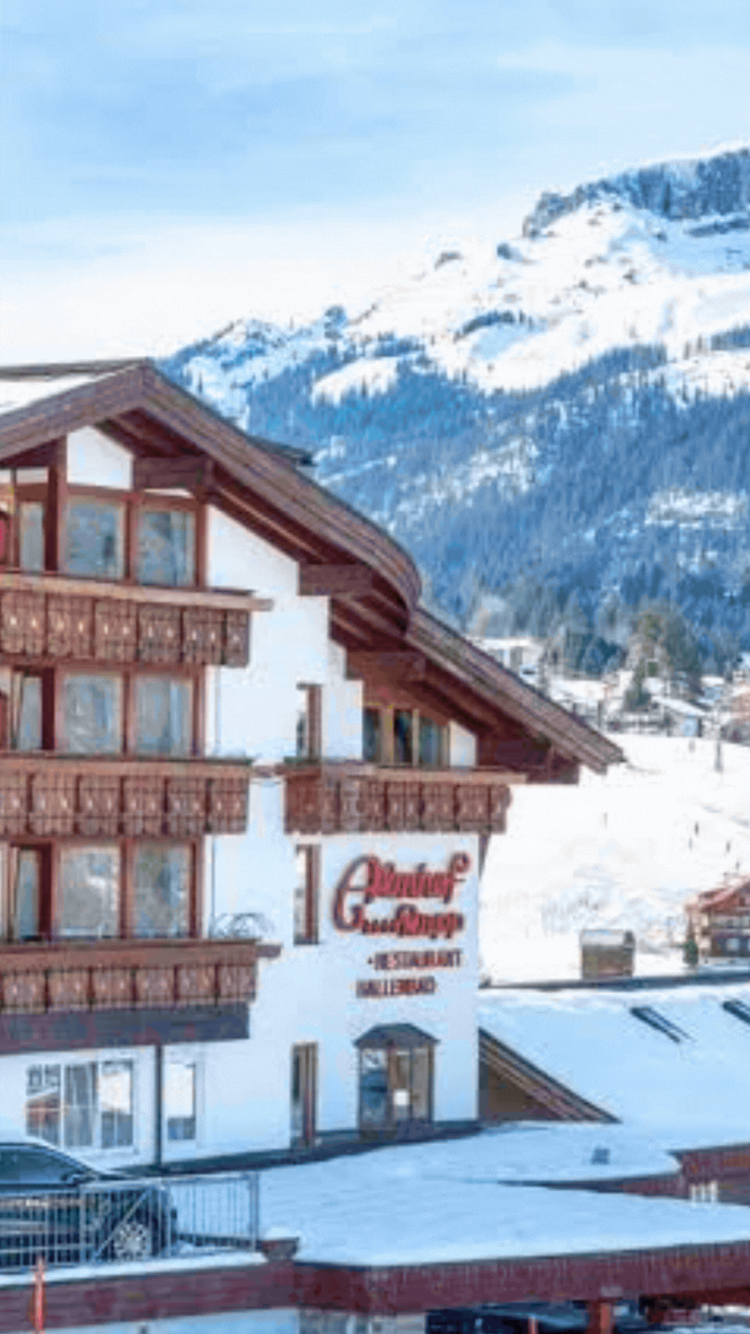 Ein Hotel mit einem Berg im Hintergrund ist mit Schnee bedeckt.