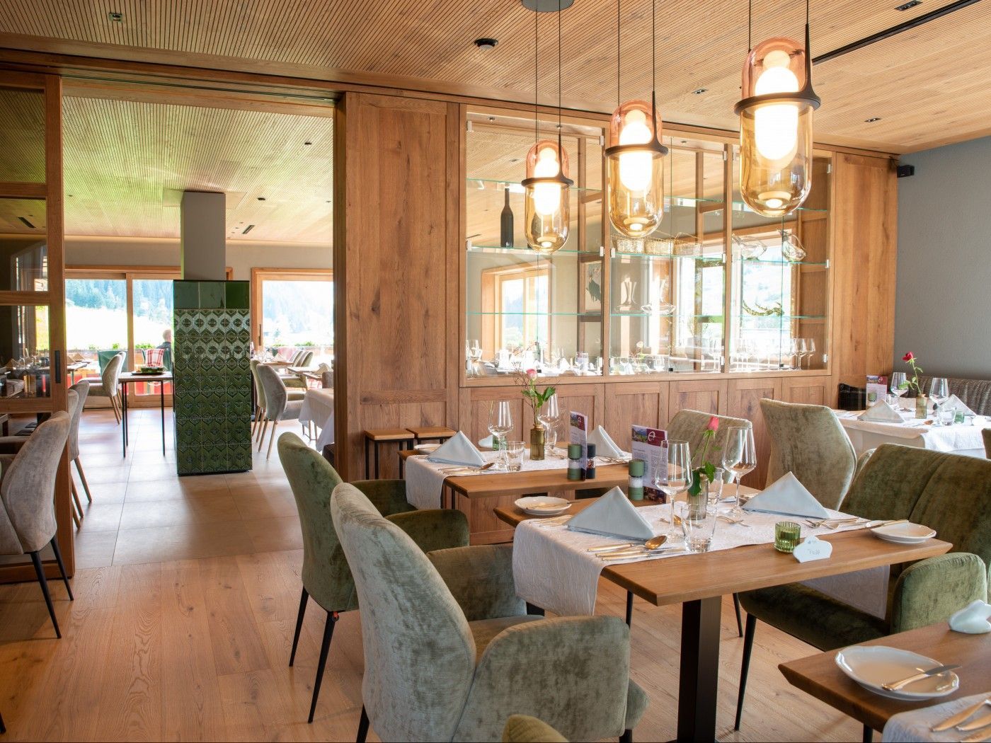 Restaurant Innenansicht des Almhof Rupp mit eingedeckten Tischen, ein Ofen im Hintergrund