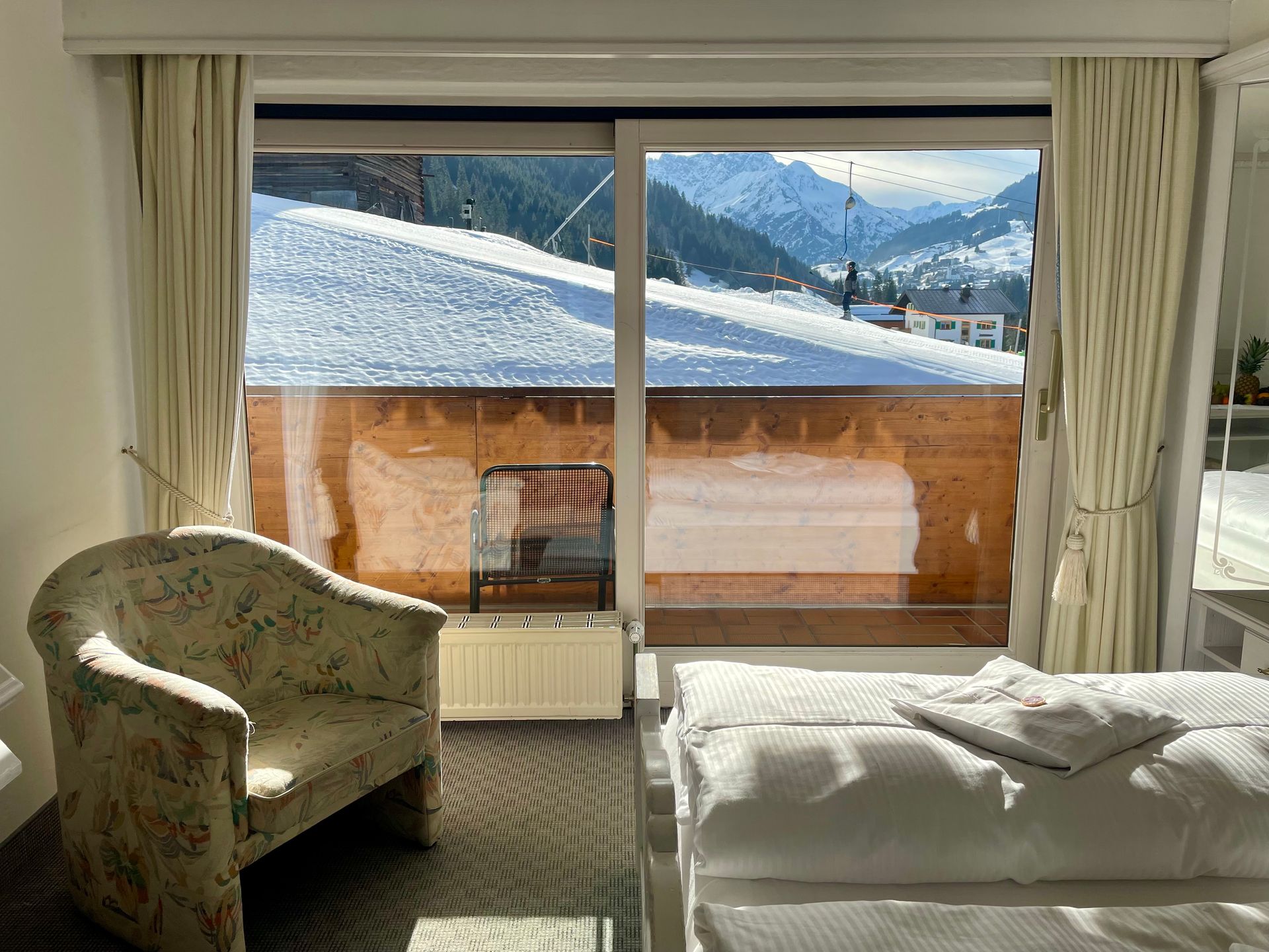 Ein Schlafzimmer mit Bett, Stuhl und Glasschiebetür mit Blick auf einen schneebedeckten Berg.