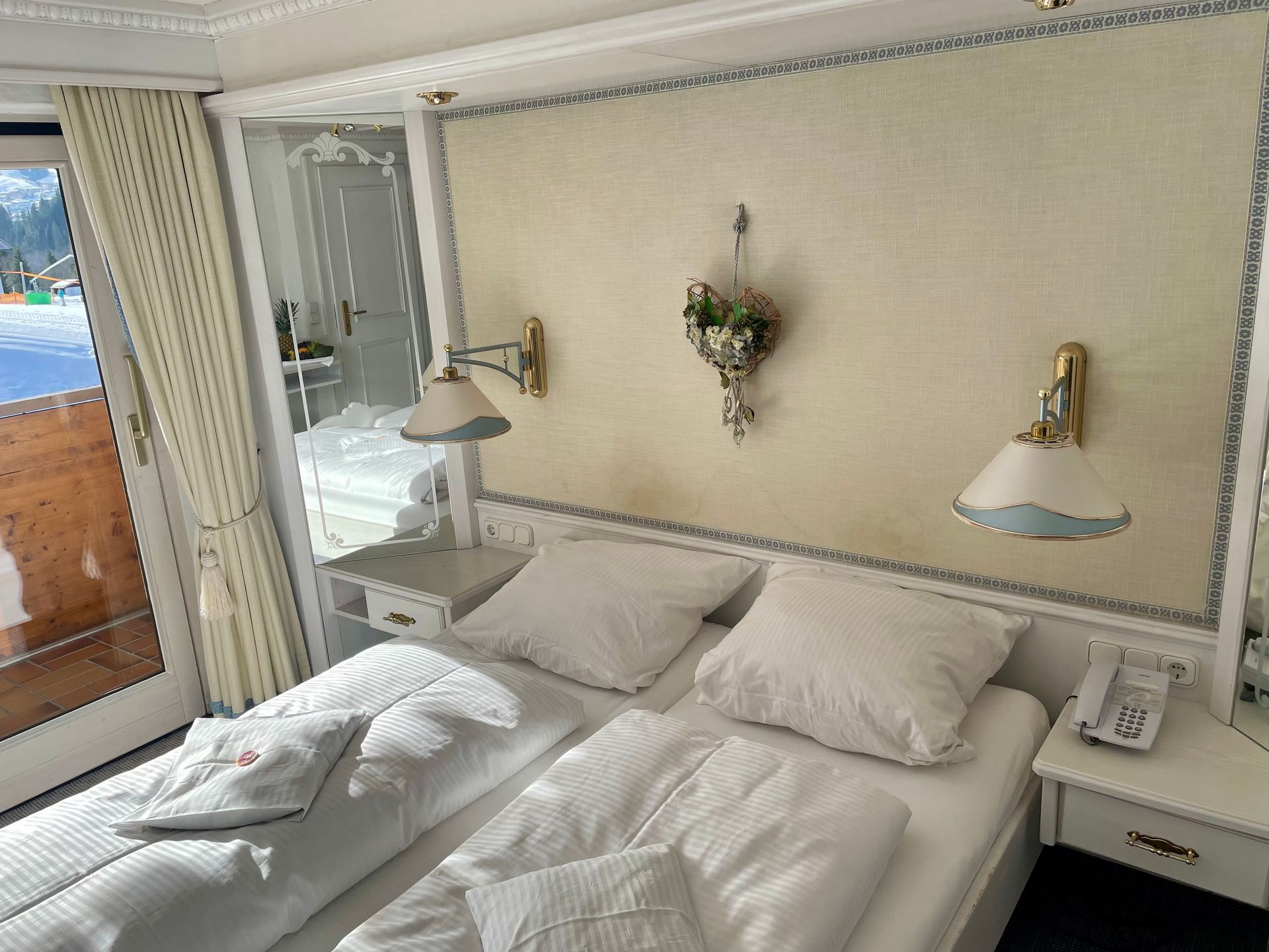 Ein Hotelzimmer mit Bett, Nachttisch, Lampen und Balkon.