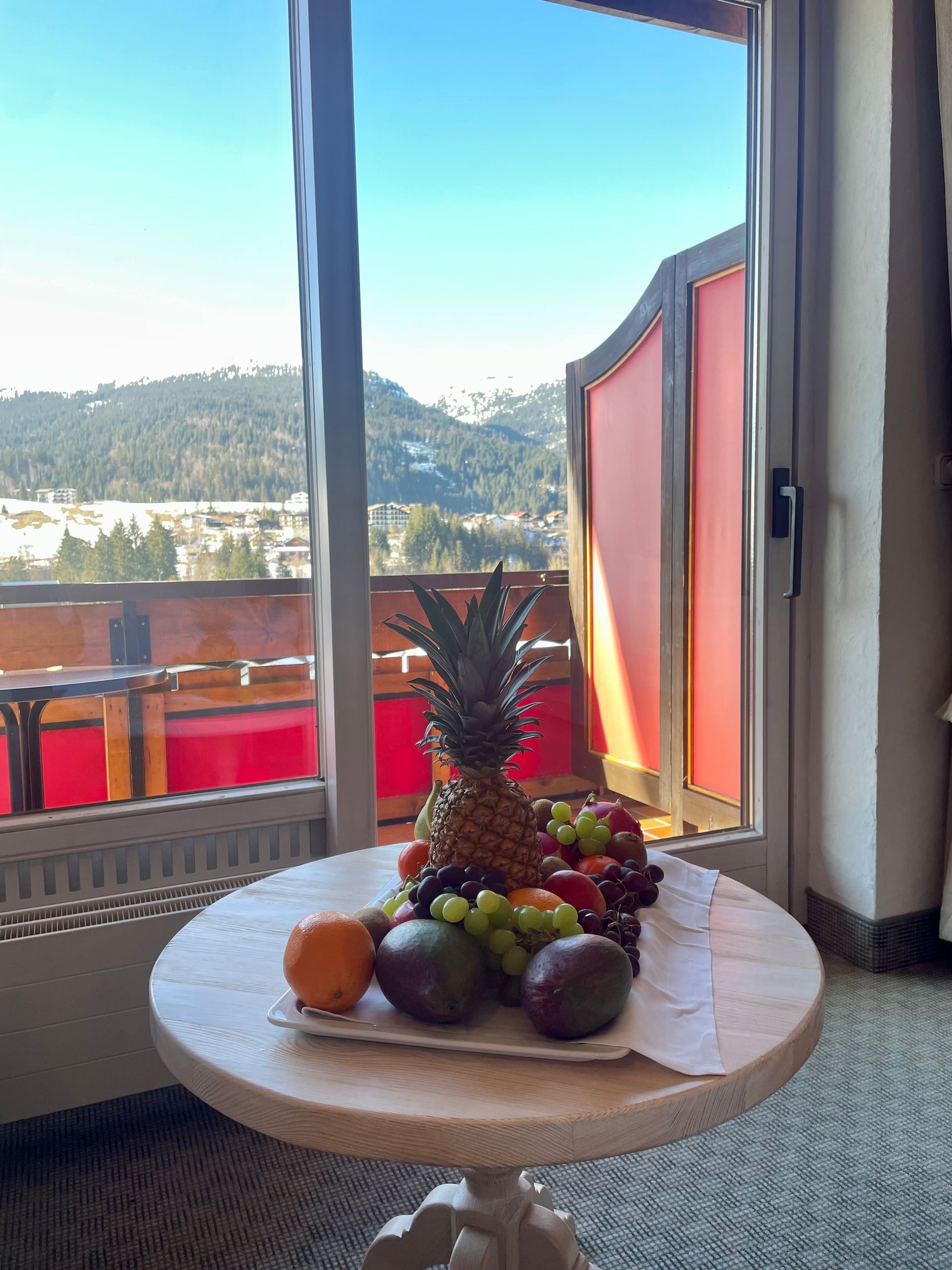 Ein Tisch mit Obst und einer Ananas darauf vor einem Fenster.
