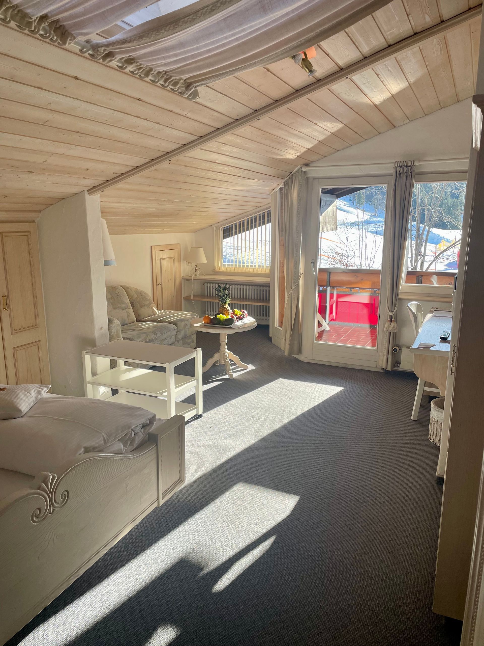 Ein Wohnzimmer mit Bett, Tisch, Stühlen und einem großen Fenster.