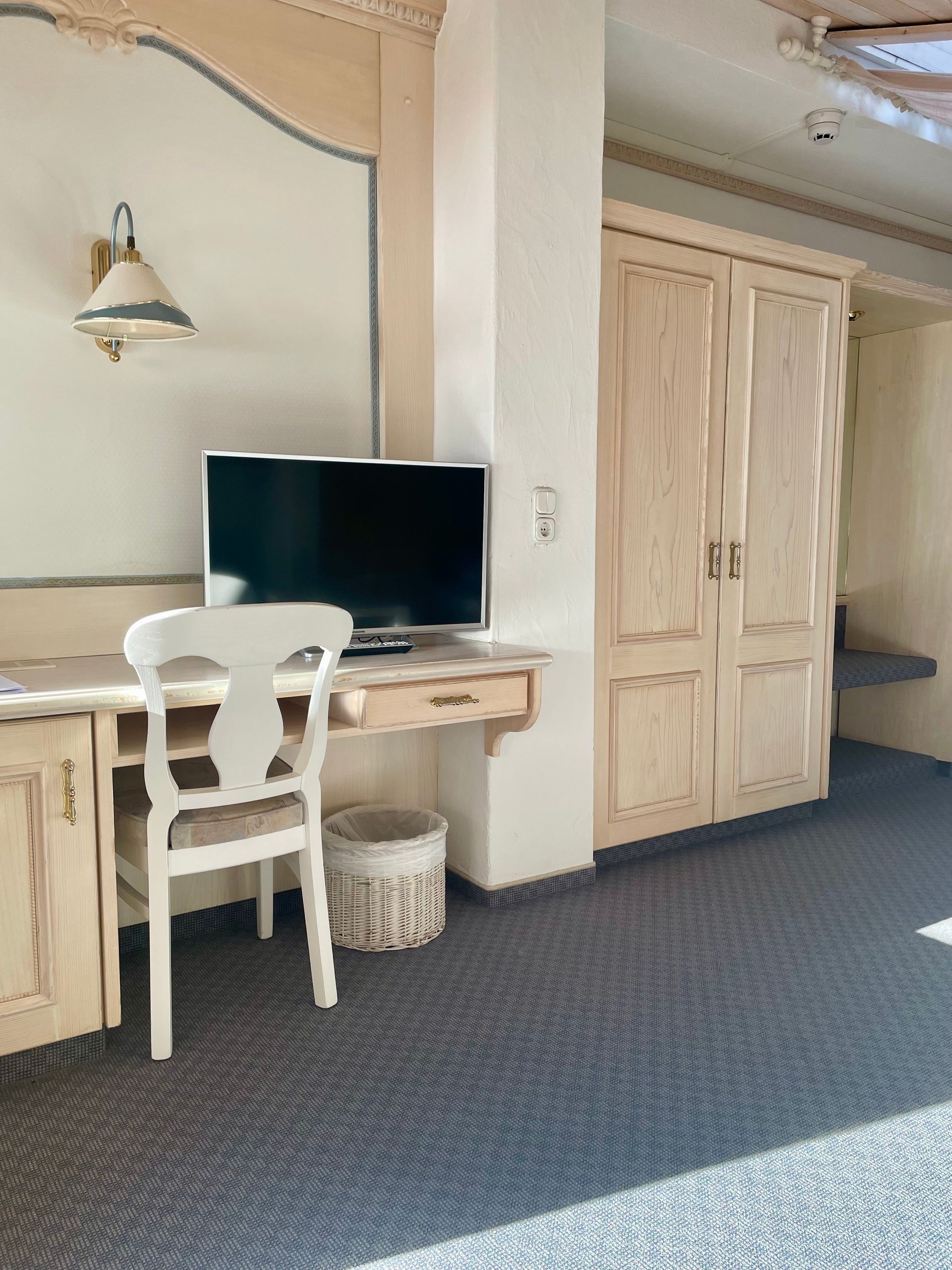 Ein Zimmer mit Schreibtisch und Stuhl und einem Flachbildfernseher