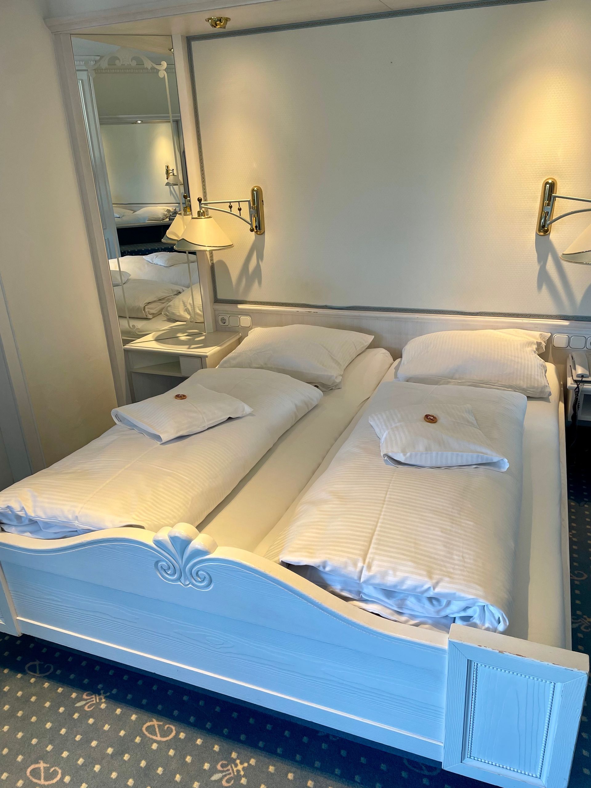 Ein Schlafzimmer mit zwei Betten und einem Spiegel an der Wand.