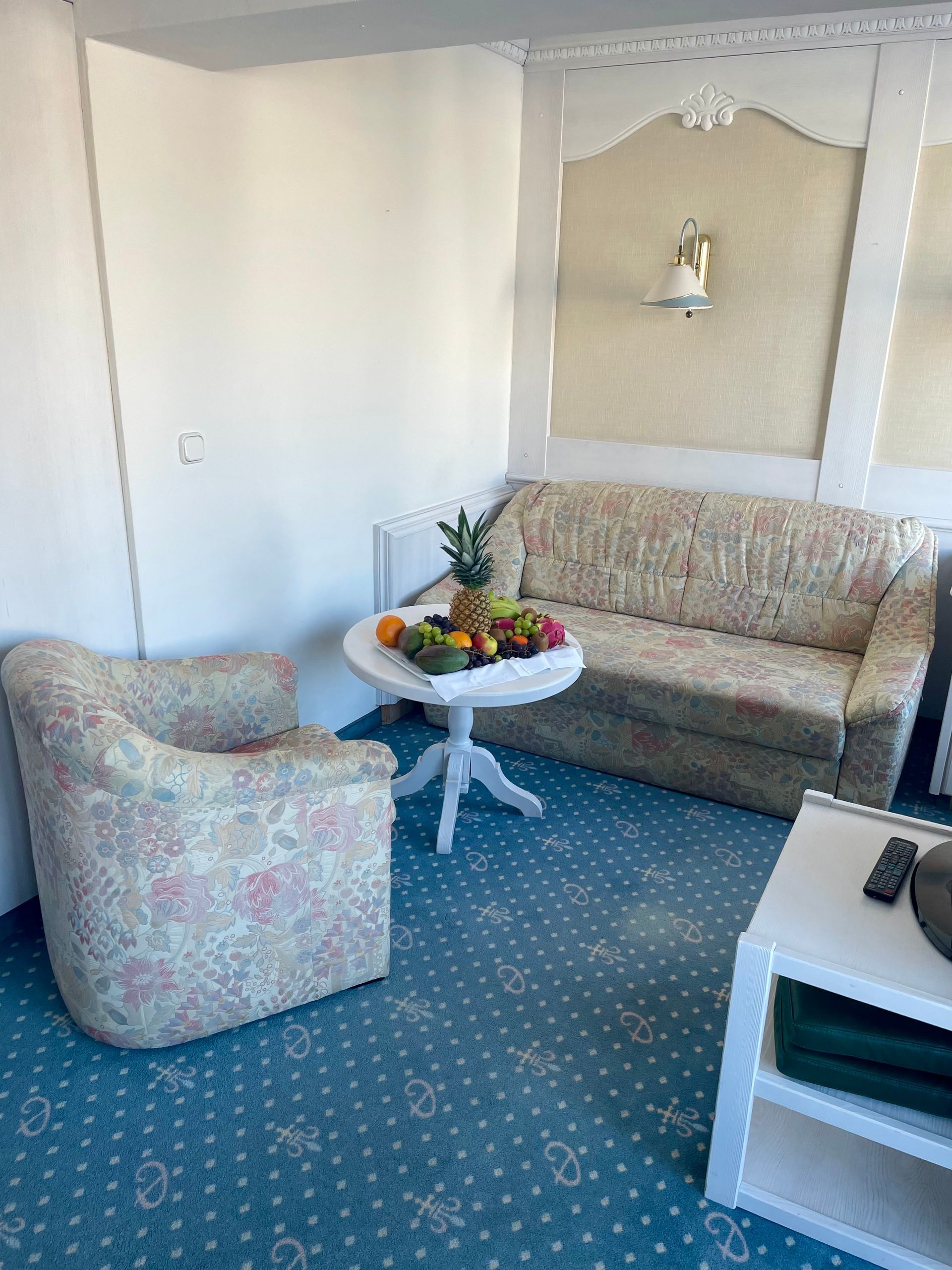 Ein Wohnzimmer mit Sofa, Sessel, Tisch und einer Obstschale.