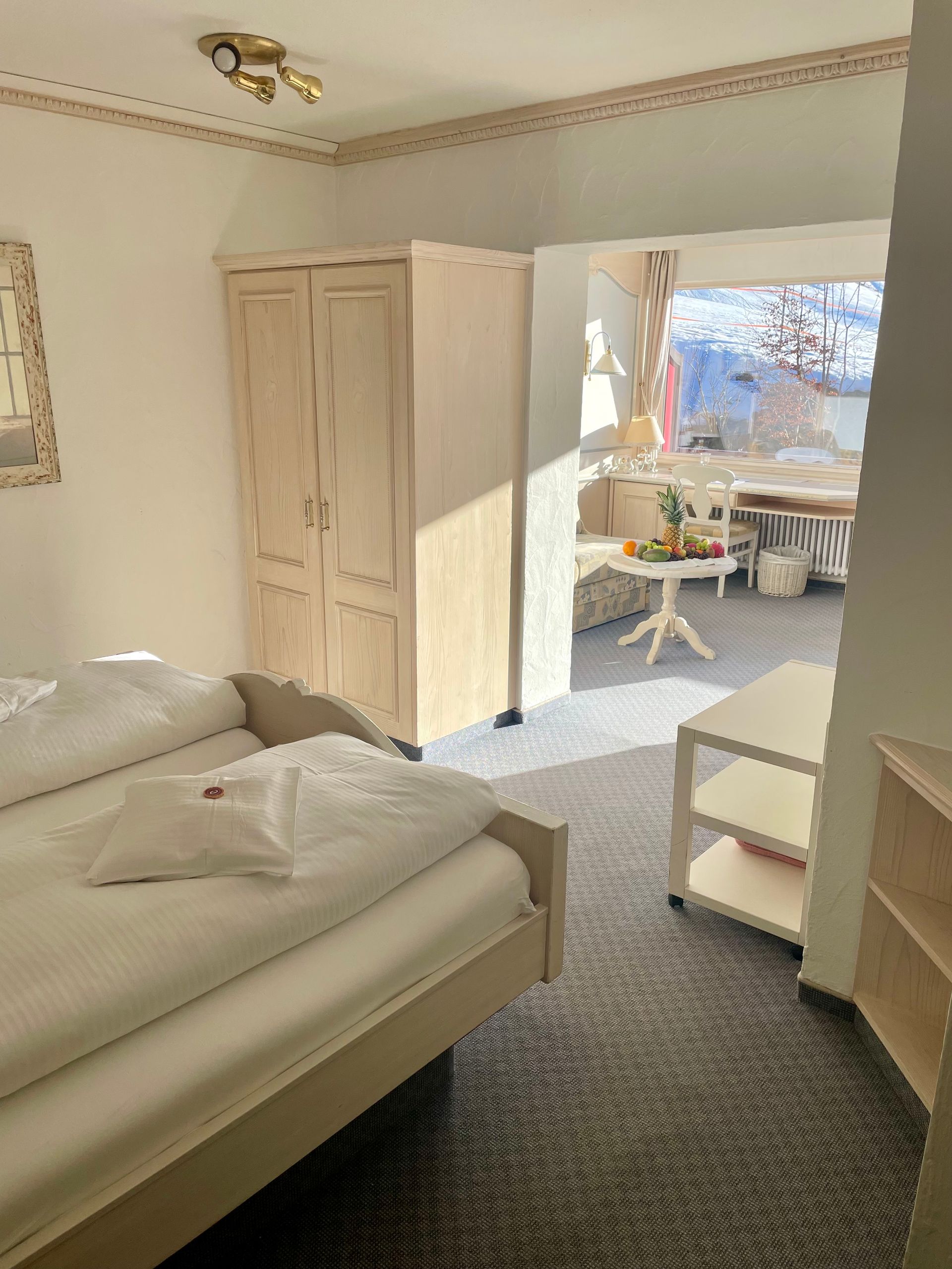 Ein Schlafzimmer mit Bett, Kleiderschrank, Tisch und Fenster.
