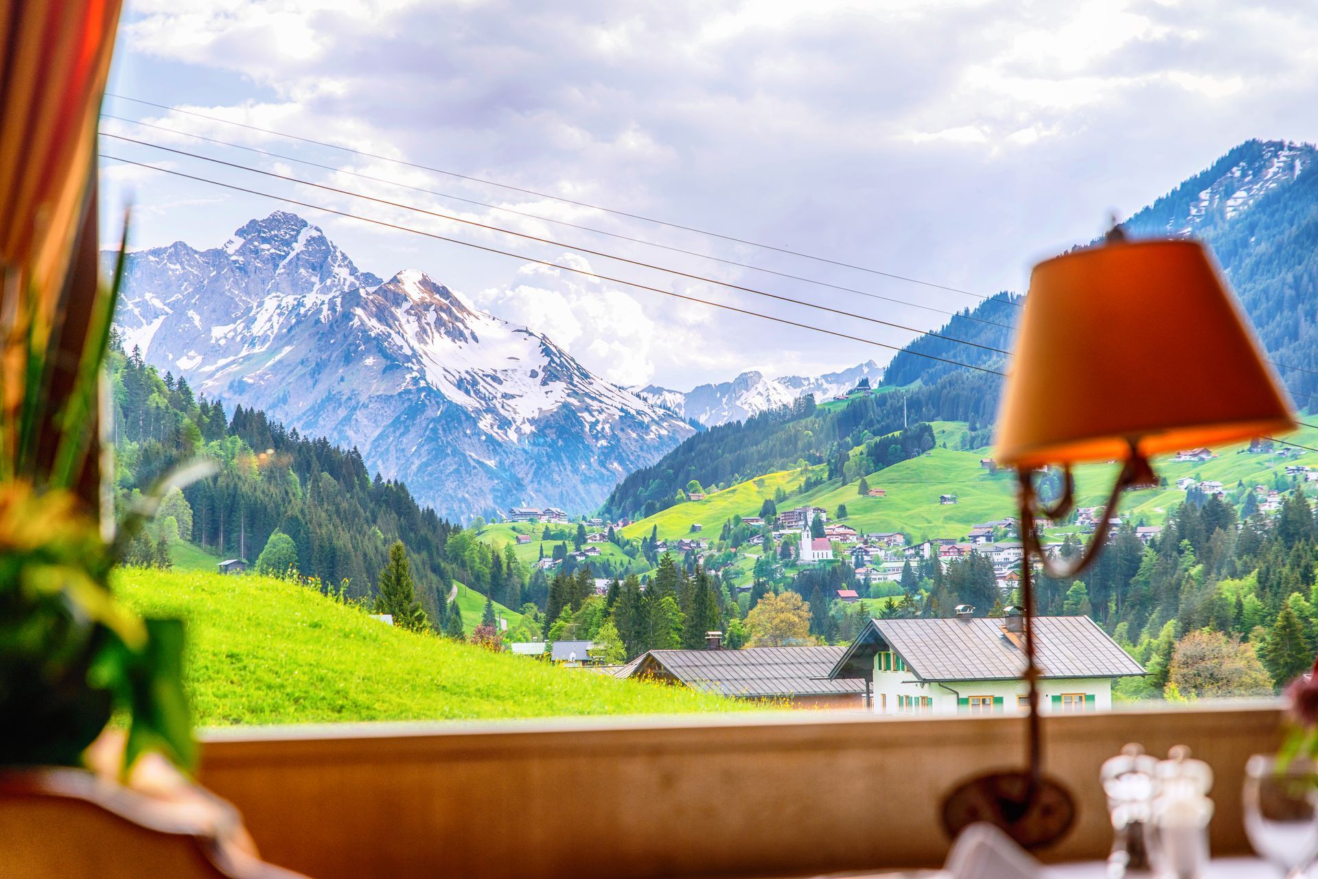 Eine Lampe steht auf einem Tisch vor einem Fenster mit Blick ins Kleinwalsertal