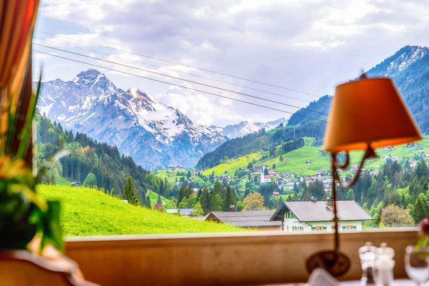 Eine Lampe steht auf einem Tisch vor einem Fenster mit Blick ins Kleinwalsertal