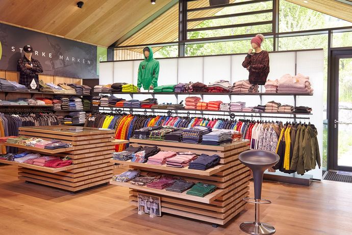 Outdoor-Bekleidungsgeschäft mit Verkaufsständern für Jacken, Hemden und Stiefel unter einer Holzdecke