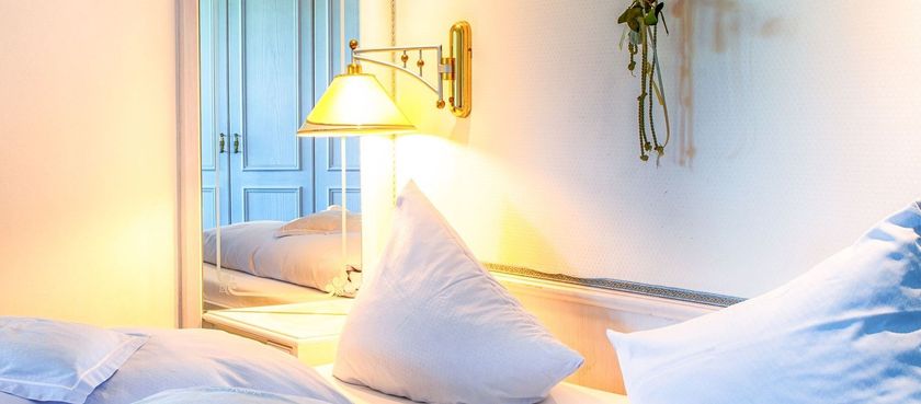 Ein Schlafzimmer mit einem Bett, Kissen, einer Lampe und einem Spiegel.
