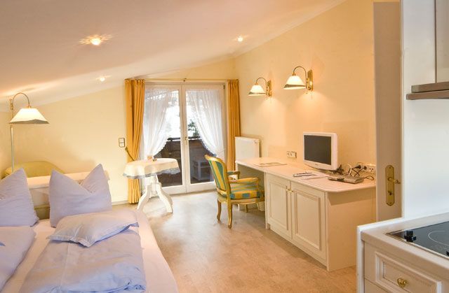 Ein Schlafzimmer mit Bett, Schreibtisch, Stuhl und Computer.