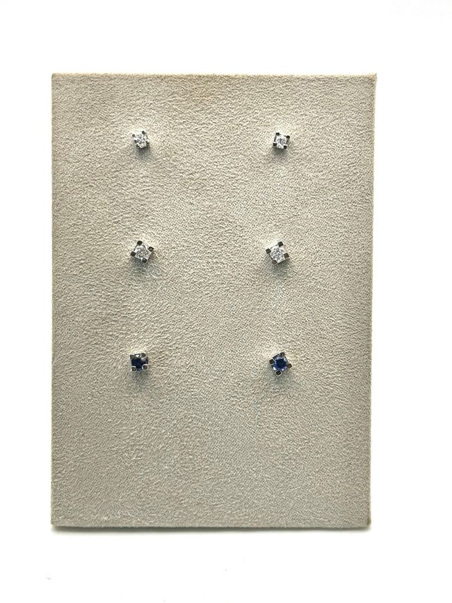 Orecchini a bottone con smeraldi esposti su un portagioie bianco all'interno di una scatola di legno.