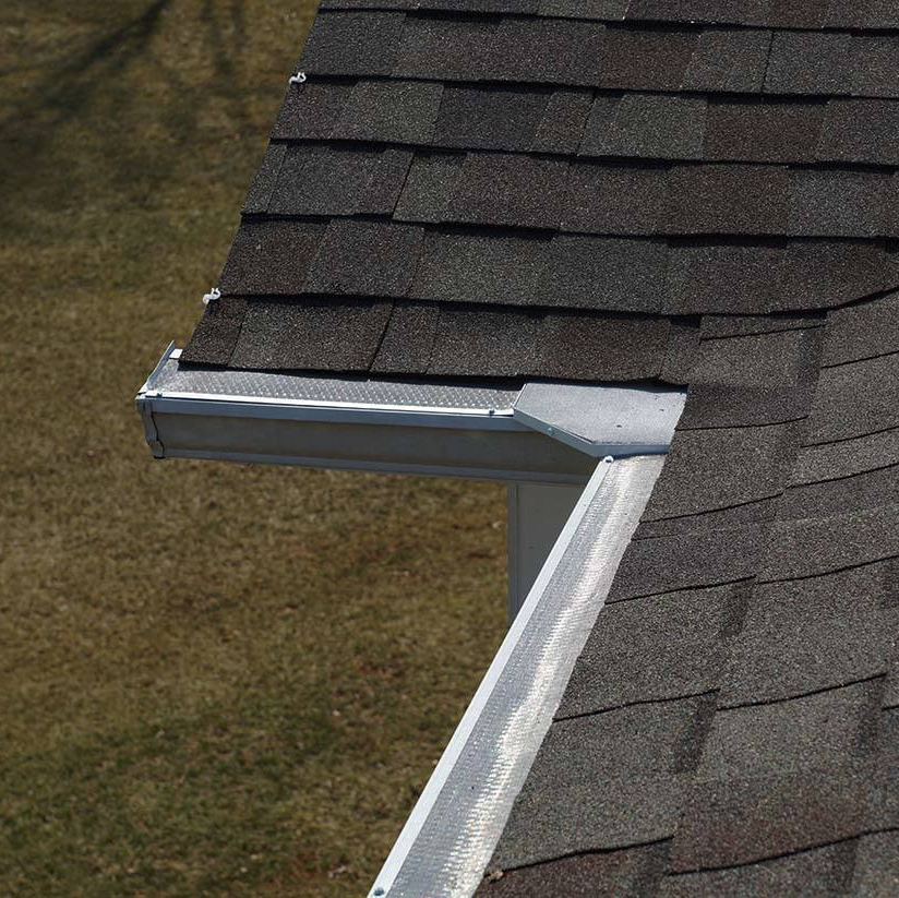 Damaged white gutter and downspout at the corner of a shingled roof
