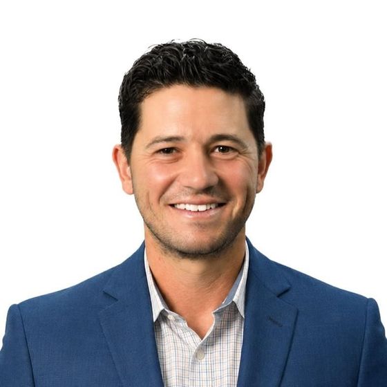 Smiling man in a blue blazer and light checkered shirt on a white background