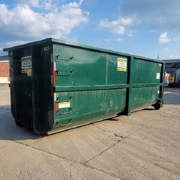 Green industrial dumpster on concrete in an outdoor setting.