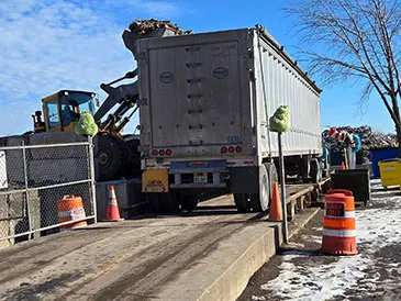 Truck being loaded with debris by a front-end loader at a recycling facility.