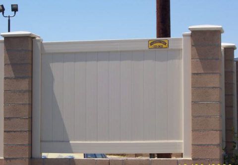 Closed white gate between brick pillars under a clear sky