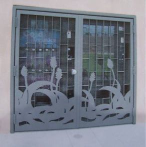 Gray metal security gate with decorative floral cutouts and wire mesh panels