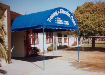 Blue awning over a building entrance, reading “Friends & Family Care” with a walkway and trees nearby