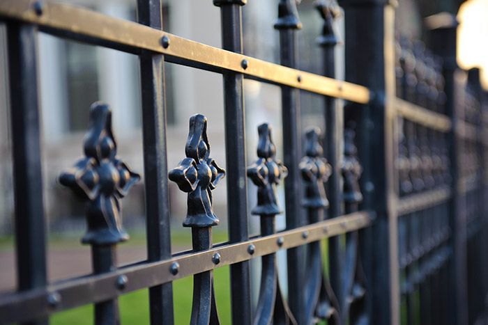 Close-up of a black wrought-iron fence with decorative spear-topped bars outdoors