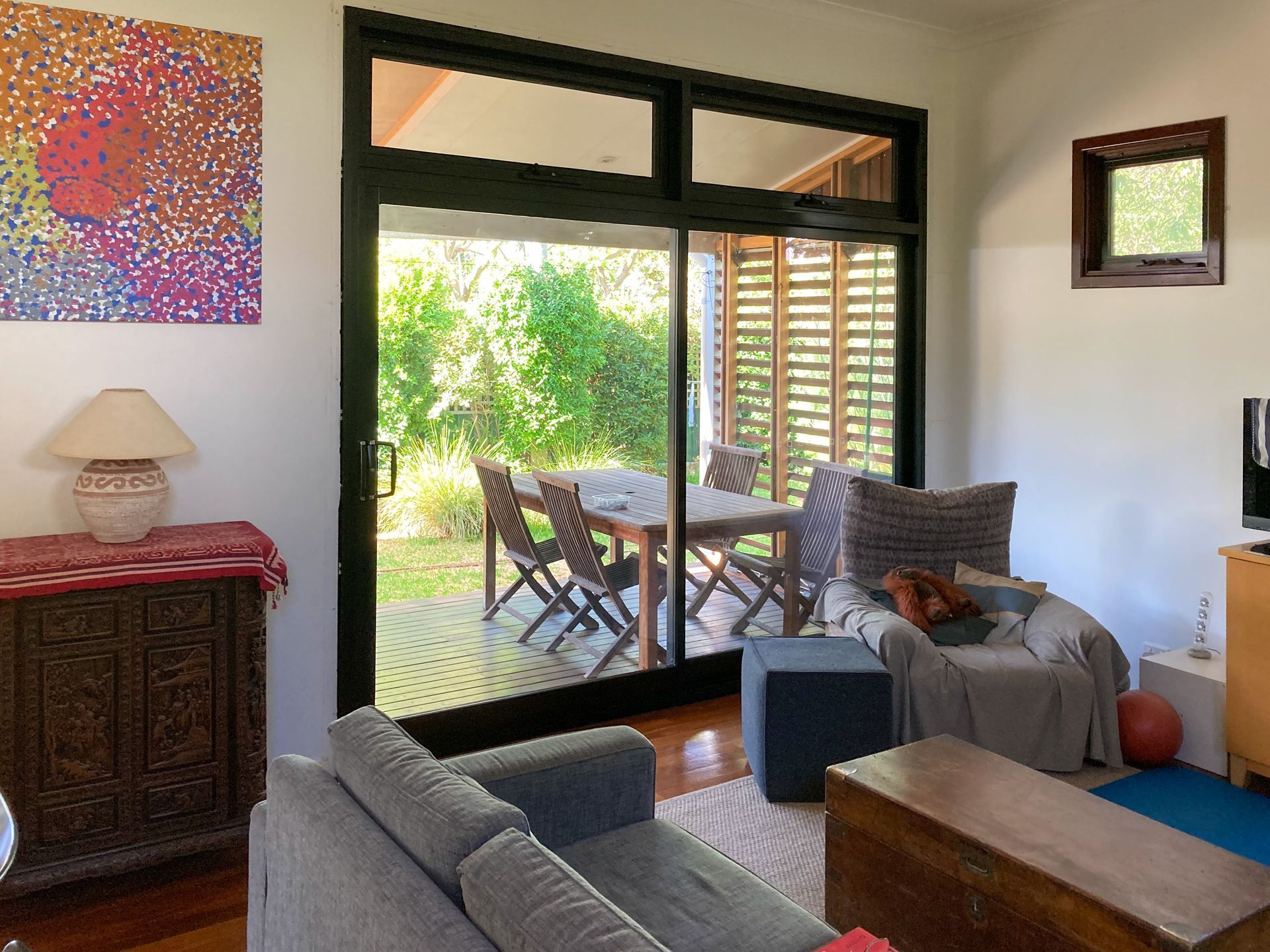 Living room with sliding door to a deck, seating, artwork, and view of outdoor dining set.