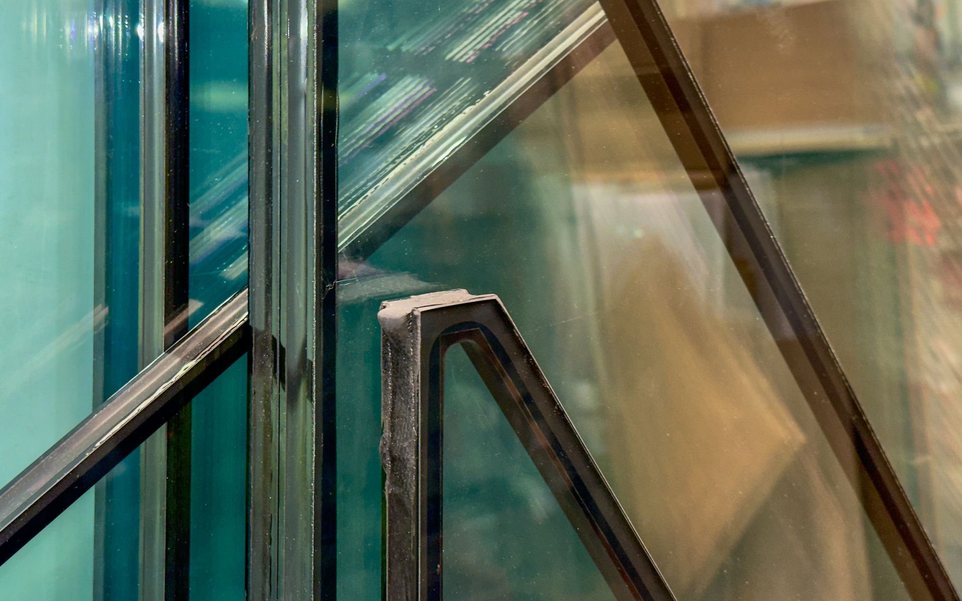 Glass panes with dark framing, overlapping at various angles, reflecting light.