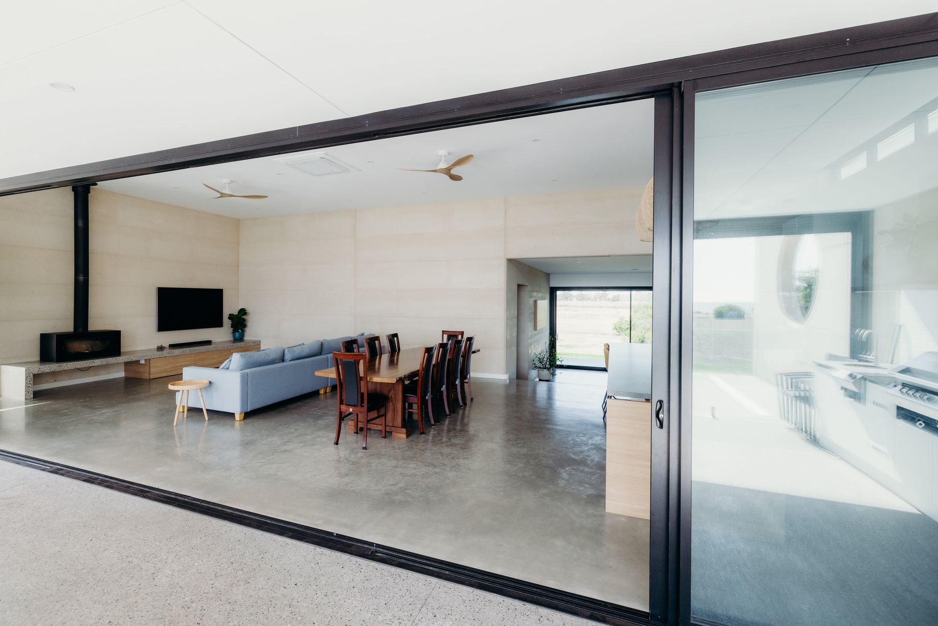 Open-plan living space with dining table, sofa, fireplace, and sliding glass doors.