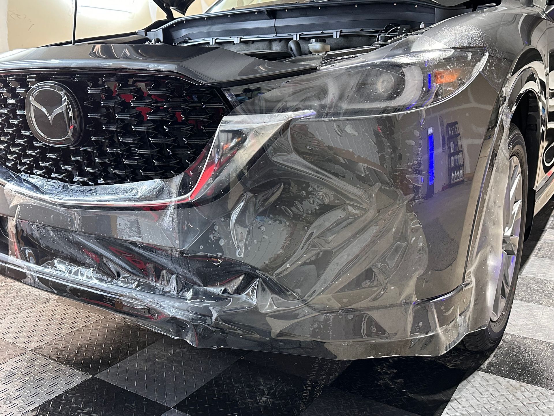 Dark gray Mazda with paint protection film applied to the bumper.