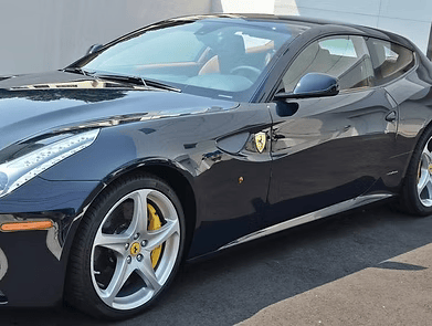 Dark blue Ferrari coupe with yellow brake calipers, parked outside.