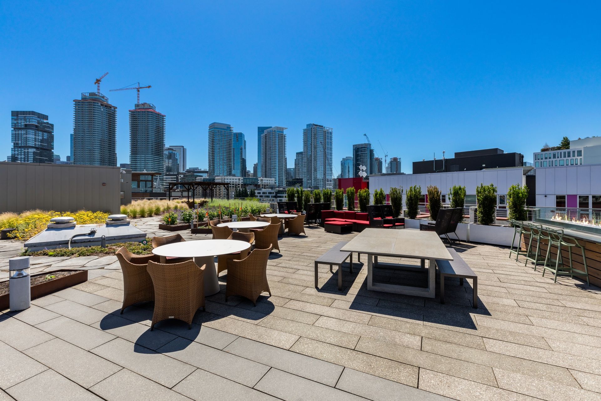 A rooftop patio with tables and chairs and a city skyline in the background