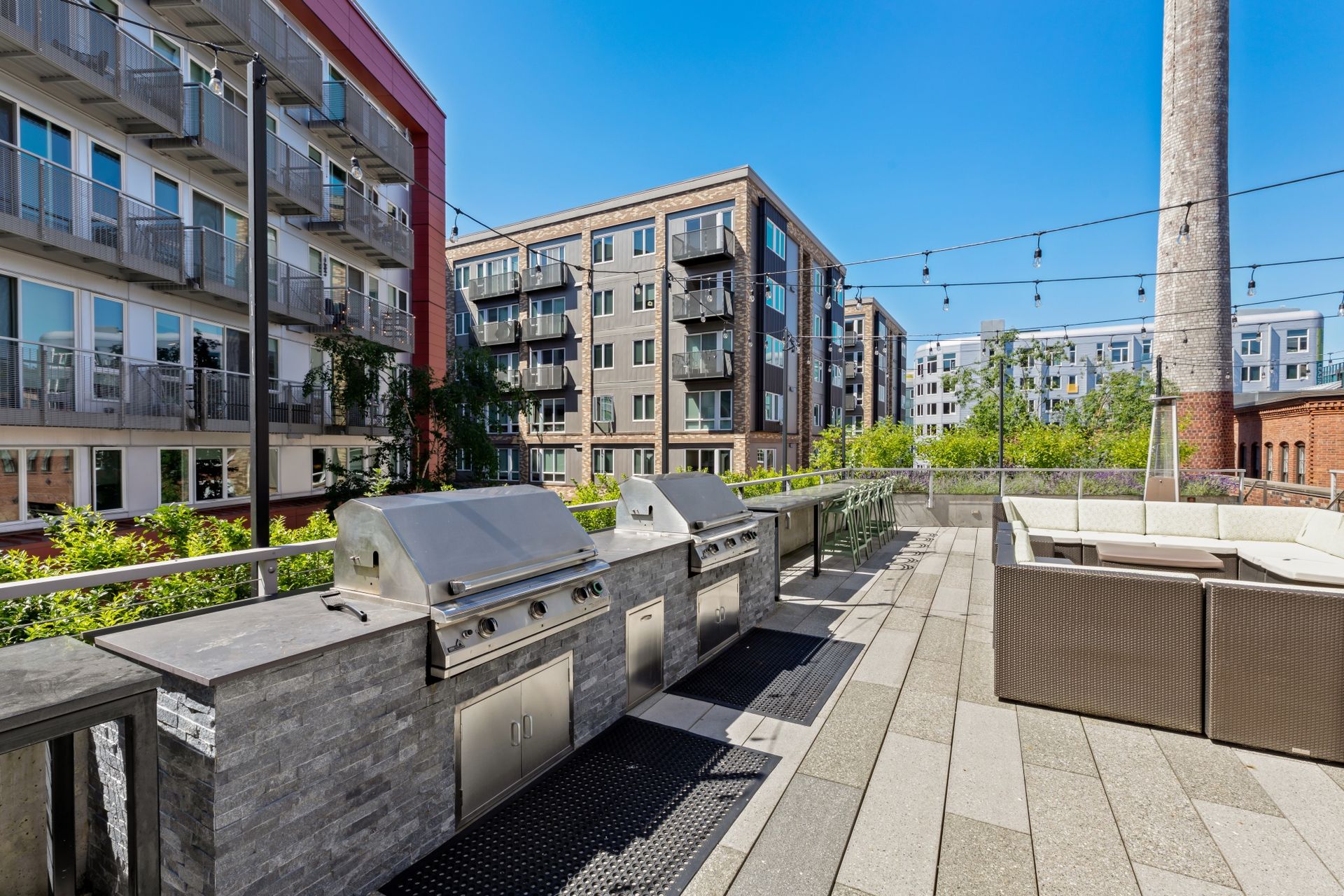 A patio with a grill and a couch in front of a building.
