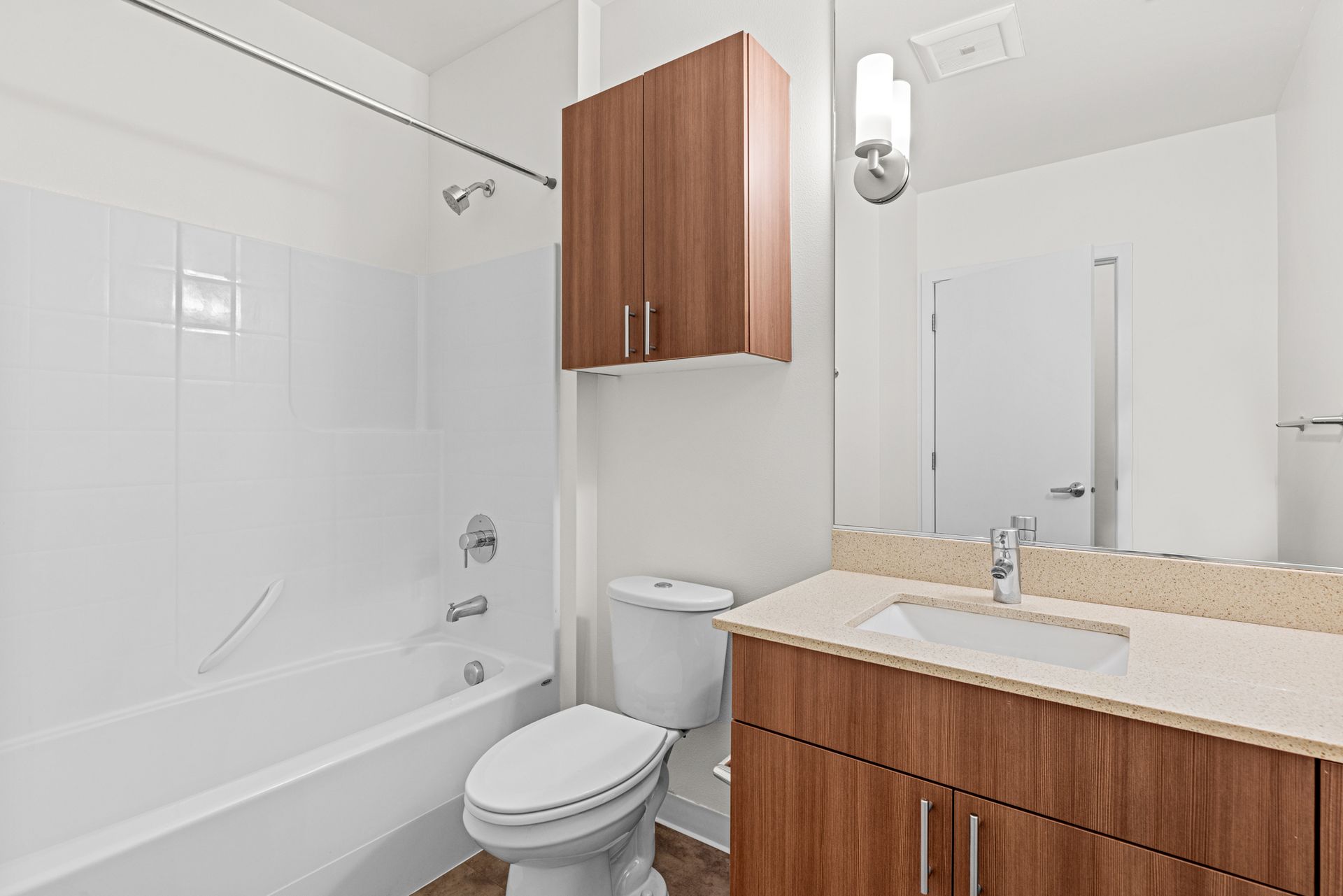 A bathroom with a toilet , sink , bathtub and mirror.