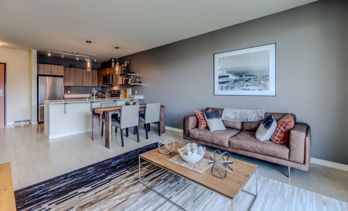 A living room with a couch , coffee table , chairs and a kitchen at Stack House.