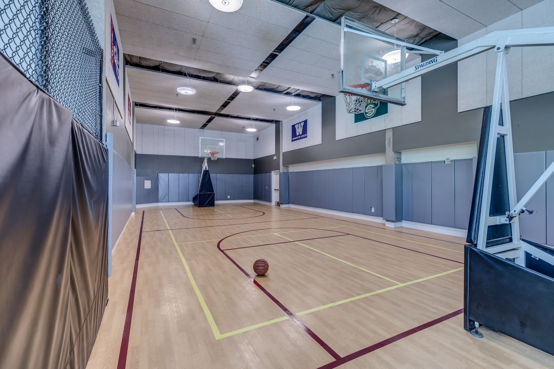 A basketball court in a gym with a basketball on the floor at Stack House.