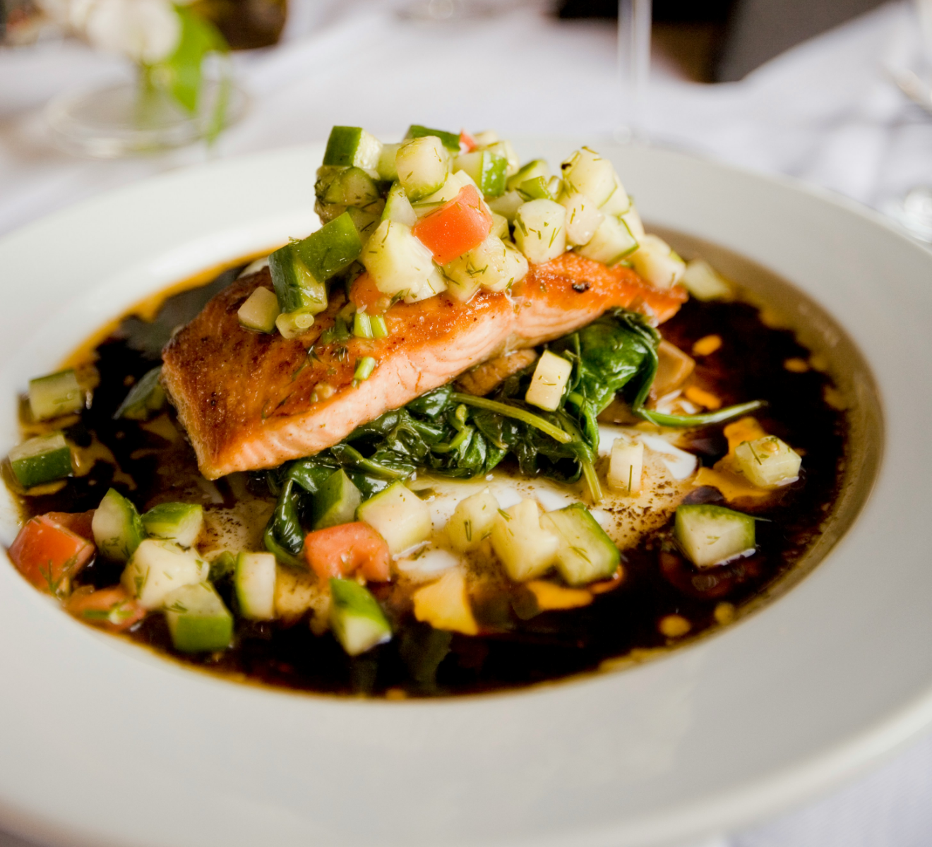 A white plate topped with a piece of salmon and vegetables