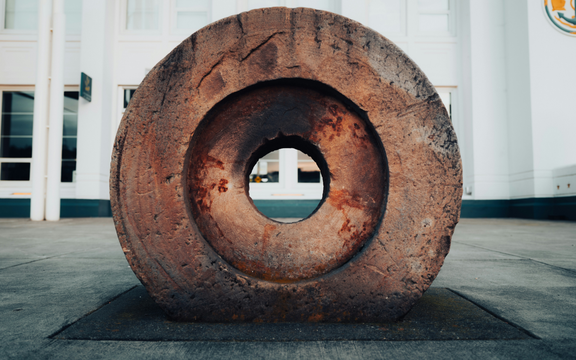 A large circular object with a hole in the middle is sitting in front of a building at Stack House.