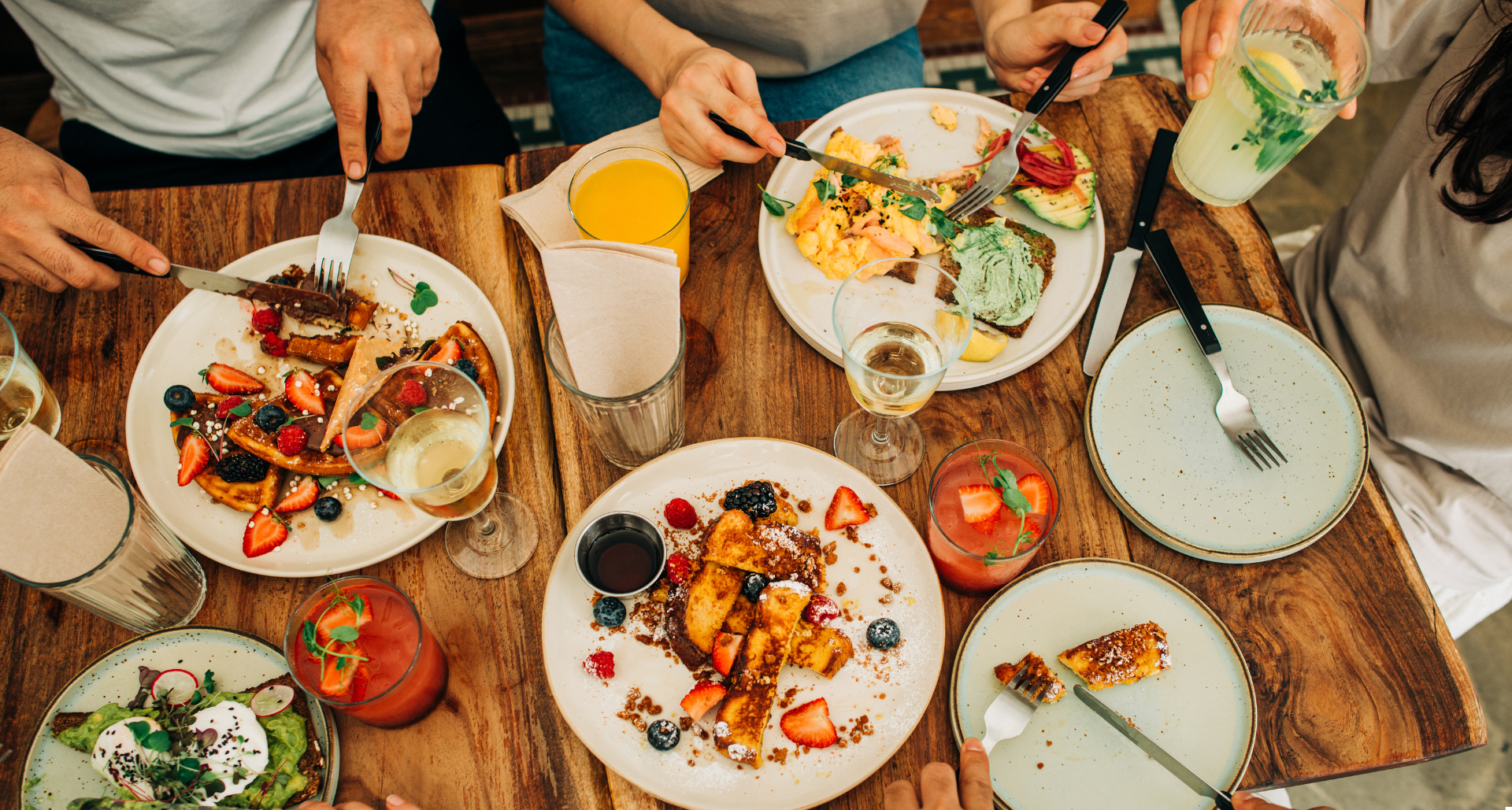 Table filled with food, drinks and people dining