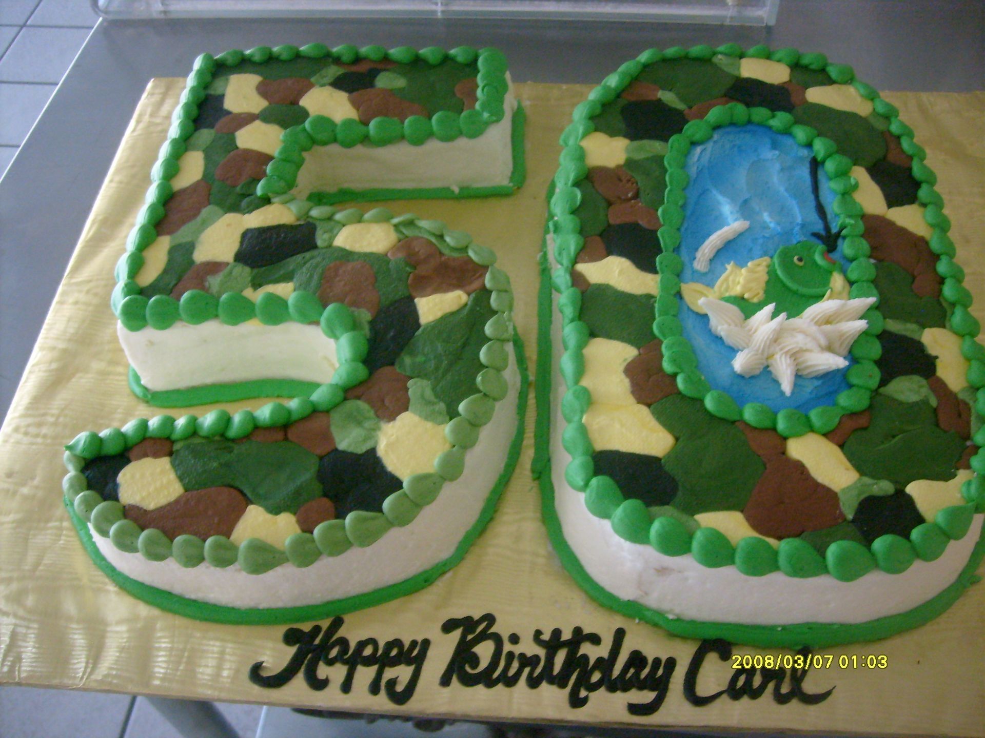 50th birthday cake decorated with green frosting, chocolate leaves, and a blue pond scene with a dragonfly topper