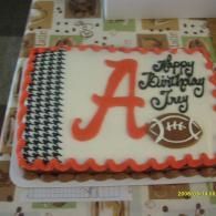 Decorated birthday cake with orange letter A, black-and-white trim, and “Happy Birthday Jay” icing.