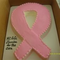 Pink ribbon-shaped cake in a box with black writing on the side.