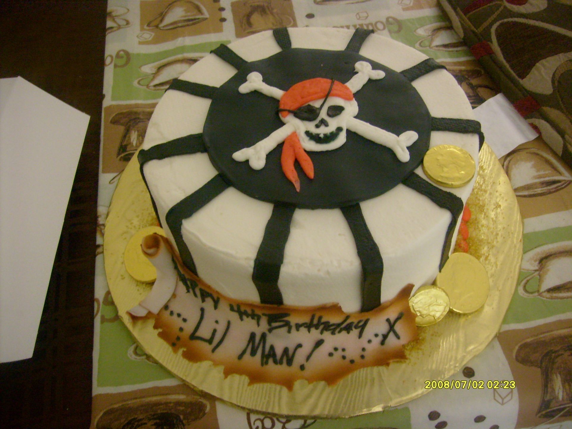 Pirate-themed cake with skull and crossbones topper and yellow decorations on a table