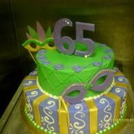 Colorful two-tier birthday cake with “65” topper, green and purple icing, and decorative swirls